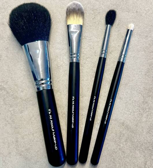foundation brush, powder brush, fluffy blender brush & lip brush in a black cosmetic zip up bag