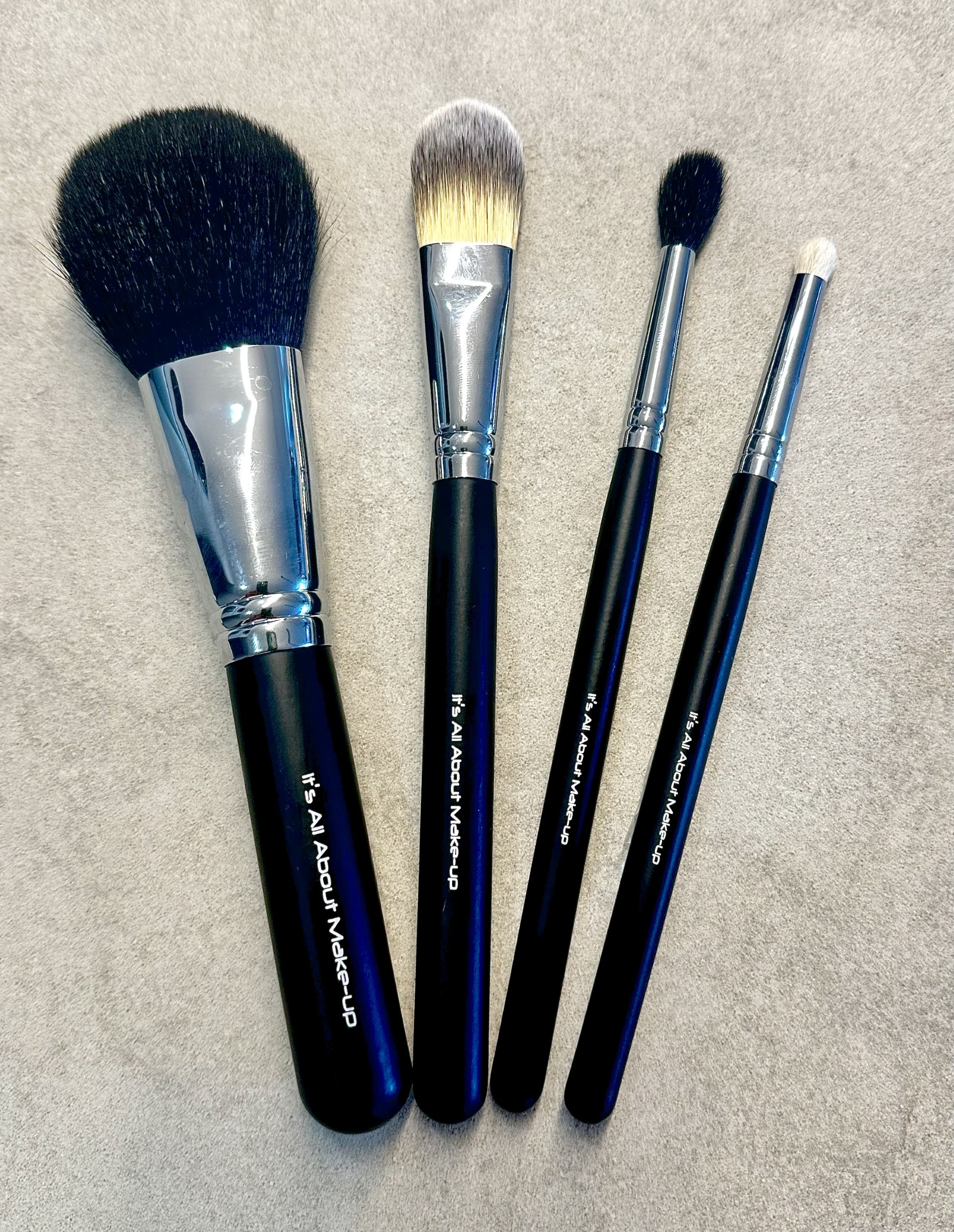 foundation brush, powder brush, fluffy blender brush & lip brush in a black cosmetic zip up bag